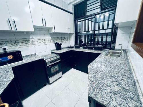 a large kitchen with black and white counter tops at The Gateway Luxury Apartment in Kigali