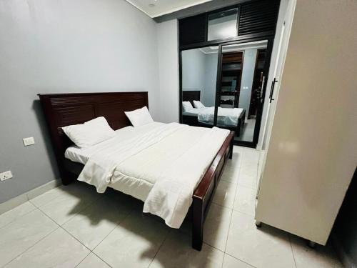 a bedroom with a large bed and a mirror at The Gateway Luxury Apartment in Kigali