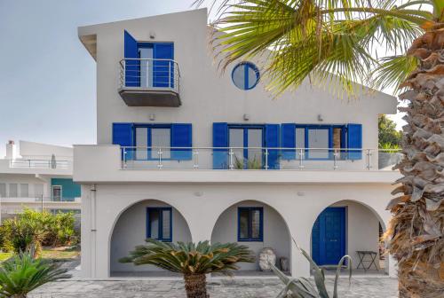 a white building with blue doors and a palm tree at Casa Azzura in Mytikas