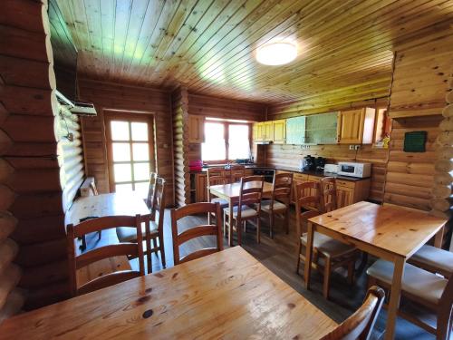 a kitchen with wooden tables and chairs in a cabin at Vili Vendégház in Demjén