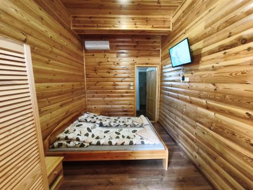 a log cabin bedroom with a bed and a tv at Vili Vendégház in Demjén