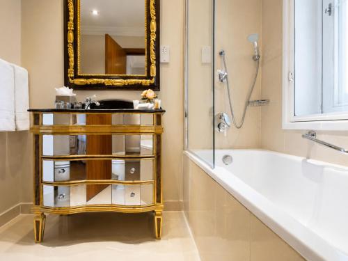 ein Badezimmer mit Waschbecken, Badewanne und Spiegel in der Unterkunft Ashburn Hotel in London