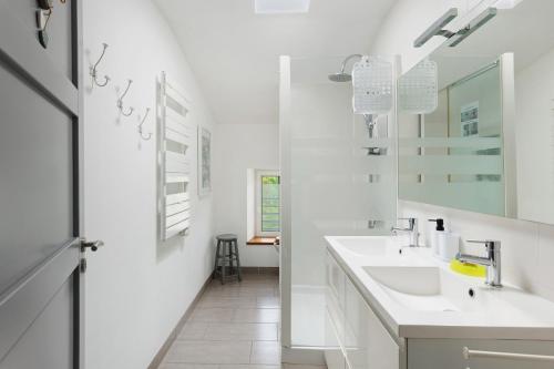 a white bathroom with two sinks and a mirror at Le Clos D'audio in Riols