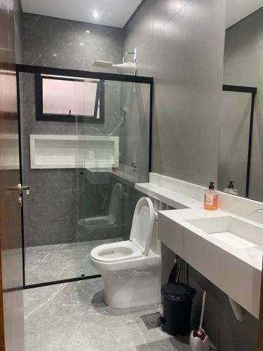 a bathroom with a toilet and a shower and a sink at Mini Palacete in Ribeirão Preto
