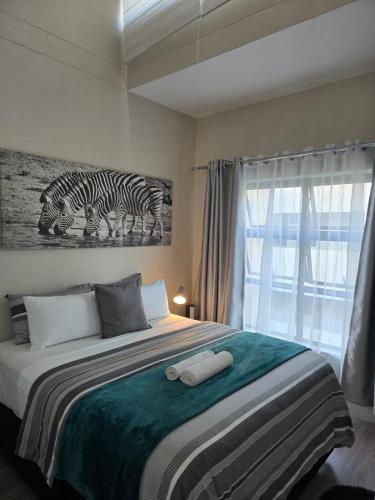 a bedroom with a bed with a painting of zebras at Beautiful 2 bedroom unit, inverter & complex pool in Johannesburg
