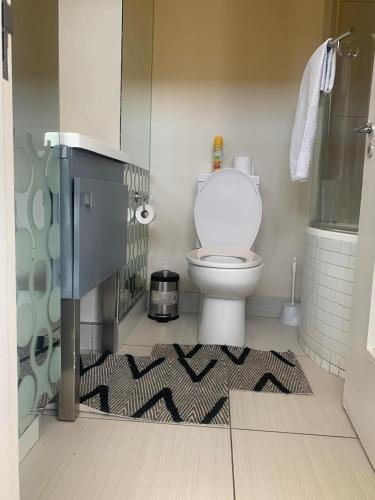 a bathroom with a toilet and a shower and a rug at Beautiful 2 bedroom unit, inverter & complex pool in Johannesburg