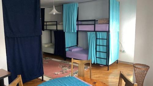 a room with two bunk beds with blue curtains at Kardelen Hostel in Prishtinë