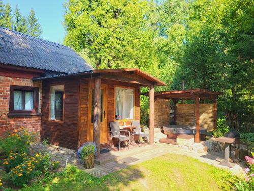 a wooden cabin with a patio with a table and chairs at LejasVāgneris in Tukums