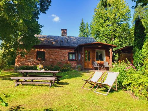a picnic table and chairs in front of a brick house at LejasVāgneris in Tukums