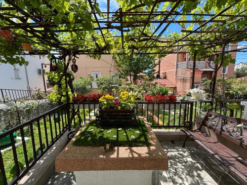 a pergola with a bench and flowers on a balcony at Kuća BORNA in Crikvenica