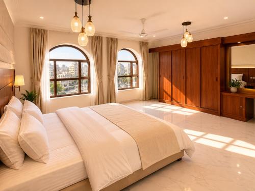 a large bedroom with a large white bed with two windows at hotel Alsalam suites in Salalah