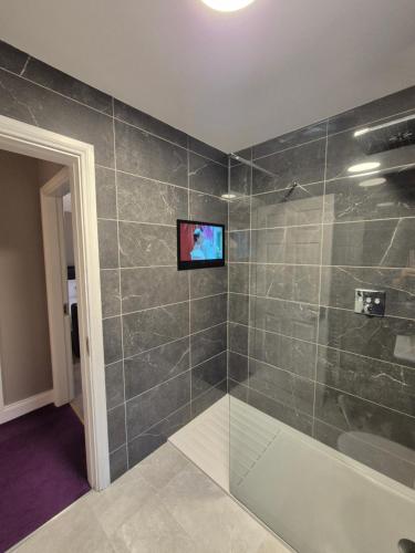 a bathroom with a shower with a television on the wall at Central House Kenmare in Kenmare