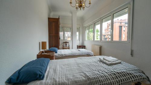 a bedroom with two beds and a chandelier and windows at Monte la Torre in Santander