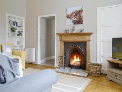 a living room with a fireplace and a television at The Old School House Cottage in Coupar Angus