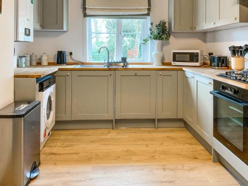 a kitchen with white cabinets and a sink at Elm Tree House - Uk51762 in Landford