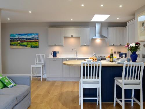a kitchen with white cabinets and a kitchen island with bar stools at Grange Loft - Uk31594 in Dundee