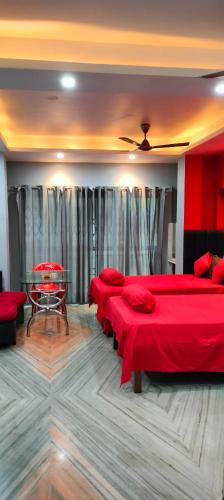 a room with three beds with red sheets and tables at Howrah Homestay Nidhivan in Howrah