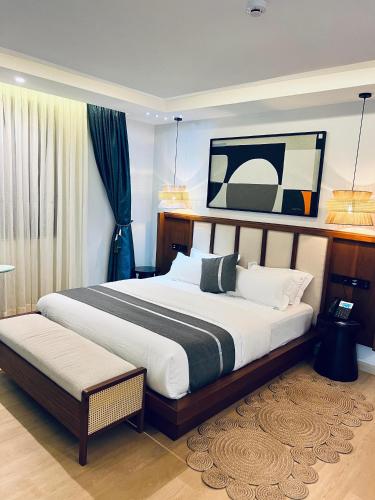 a bedroom with a large bed and a bench in it at Eza Hotel in Kigali