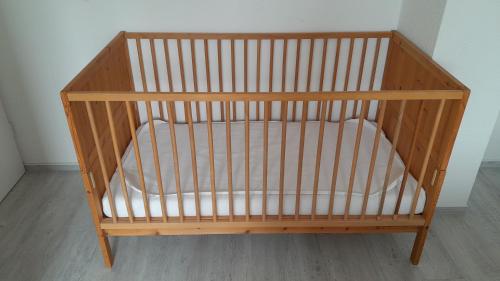 a wooden crib with a white seat in a room at 'Seeperle' am Strand des Kummerower Sees in Verchen