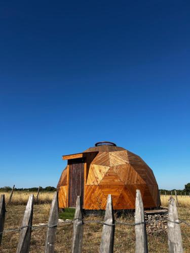 a wooden building in a field behind a fence at Dôme géodésique in Brie