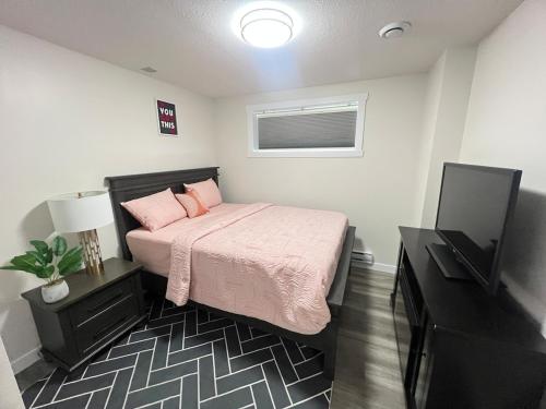 a bedroom with a bed with pink sheets and a television at Purplecherry Haven in Regina