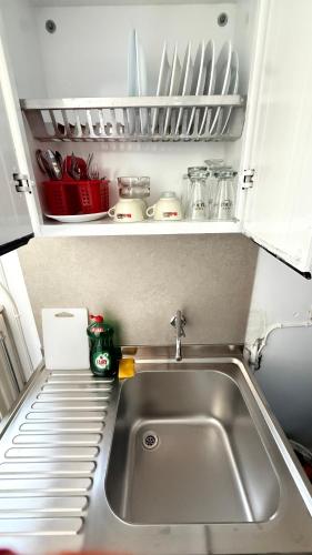 a kitchen with a sink and a shelf with dishes at Naxos City Hostel in Naxos Chora