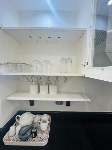 a shelf with cups and dishes on it in a kitchen at The Sails-Luxe Penthouse By Ezey Tours in Durban