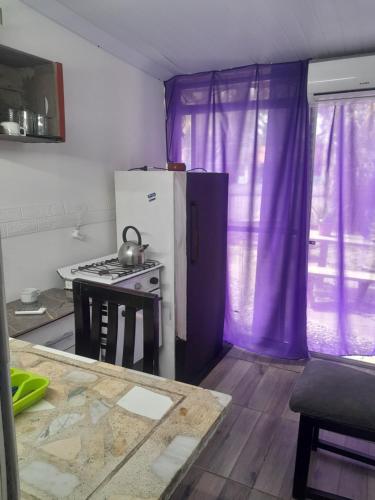 a kitchen with a refrigerator and a stove with purple curtains at Canela in Atlántida