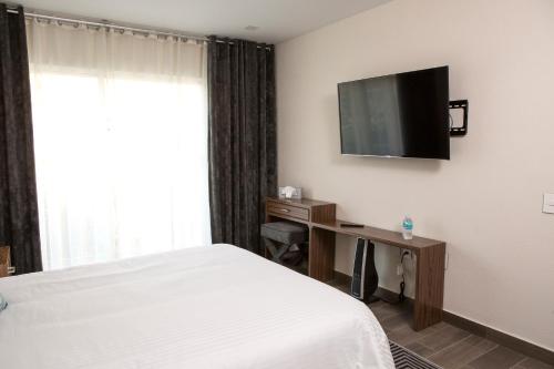 a hotel room with a bed and a desk and a television at Suites Rio Elba in Mexico City