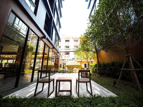 three chairs and a table in front of a building at 130 Hotel & Residence Bangkok in Bangkok