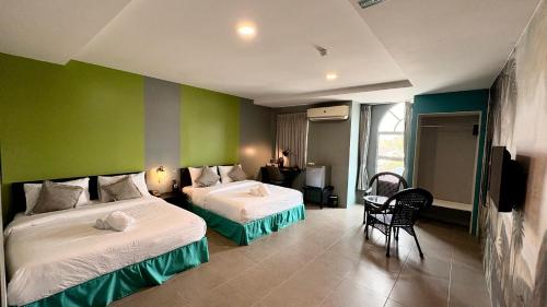 a bedroom with two beds and a green wall at Metroinn Hotel in Arau