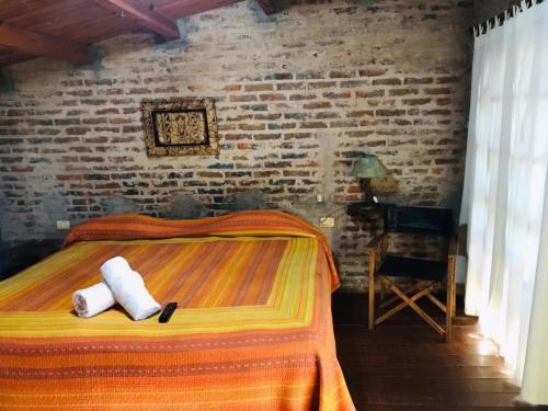 ein Schlafzimmer mit einem Bett und einer Ziegelwand in der Unterkunft Hotel Jasy in Puerto Iguazú