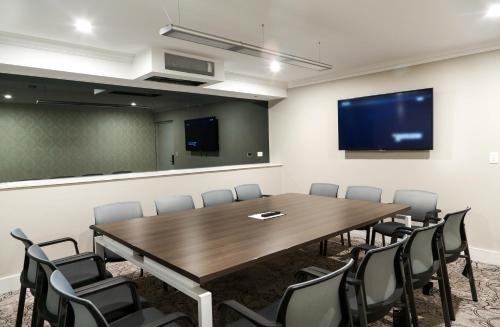 a conference room with a large wooden table and chairs at The Lurline Randwick in Sydney