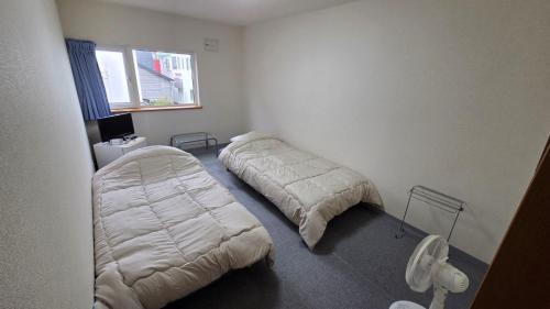 a bedroom with two beds and a window at Shimano Yado Rishirikuru in Rishiri