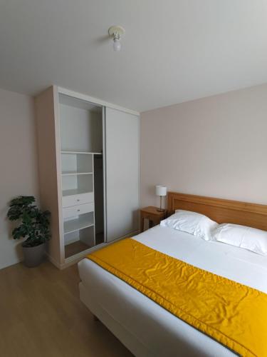 a bedroom with a large bed with a yellow blanket at Domitys Le Griffon d’Or in Saint-Brieuc