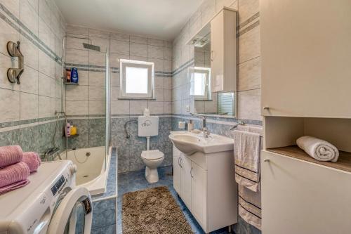 a bathroom with a sink and a washing machine at Apartments Celebrini in Malinska