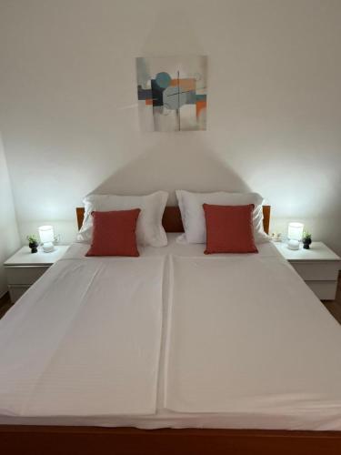 a white bed with two red pillows on it at Apartment Near Zadar Airport & City in Crno