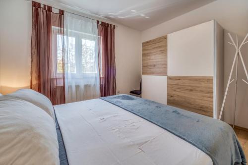 a bedroom with a large bed and a window at Apartments Celebrini in Malinska