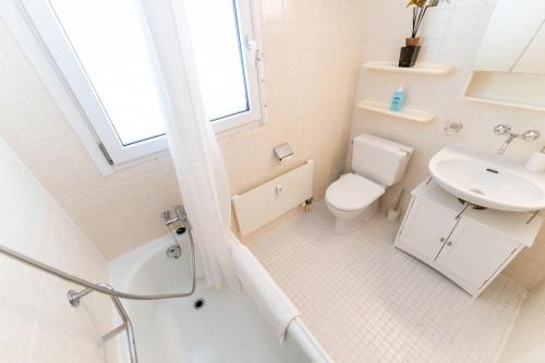 a white bathroom with a toilet and a sink at Cozy Swiss Apartment - City & Mountain view in Interlaken