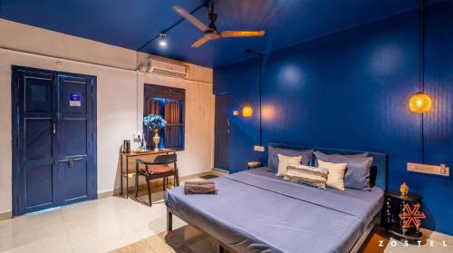 a blue bedroom with a bed and a chair at Zostel Alleppey in Alleppey