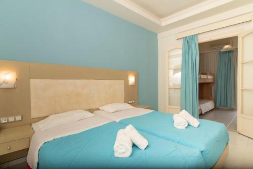 a bedroom with a blue bed with towels on it at Porto Koukla Beach in Lithakia