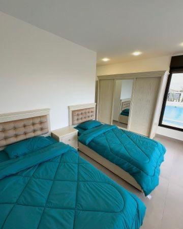 a bedroom with two beds with blue pillows at Olives Hill Farm in Al Kufayr