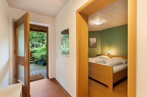a bedroom with a bed and a door to a patio at Haus Ersfeld – Gartenwohnung in Bad Teinach-Zavelstein