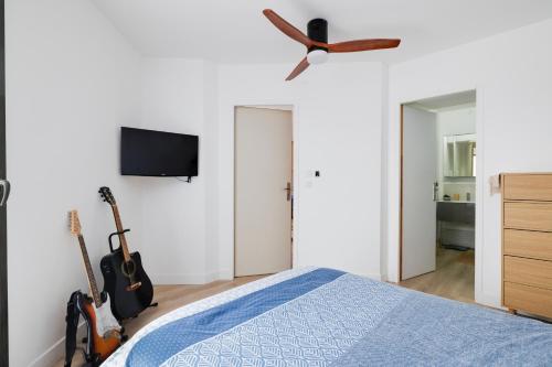 a bedroom with a bed with a ceiling fan and guitars at Comfy Counord place in Bordeaux
