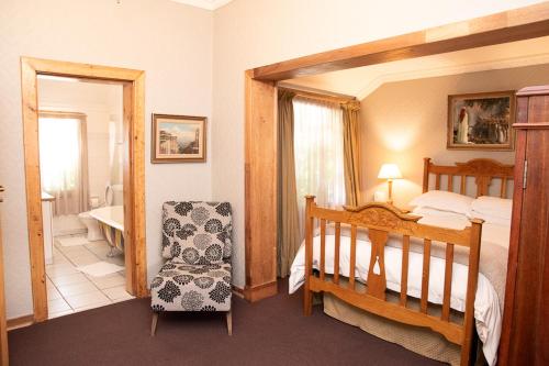 a bedroom with a bed and a chair and a crib at Hobbit Boutique Hotel in Bloemfontein