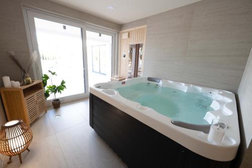 a large bath tub in a room with a large window at Kálló Villa in Nagykálló