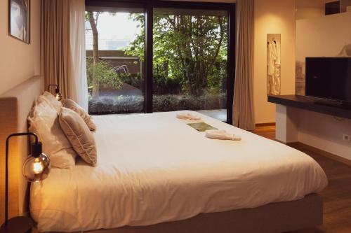 a bedroom with a large bed with a large window at Huyze Fox - Boutique Stays in Bruges