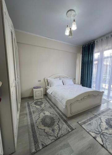 a bedroom with a white bed and a large window at Гостевой дом Кымбат in Chok-Tal