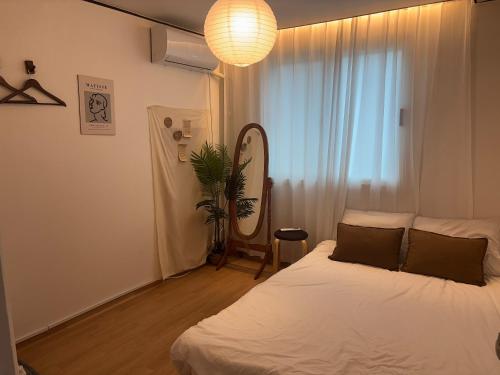 a bedroom with a bed and a mirror and a lamp at Coco House in Daejeon