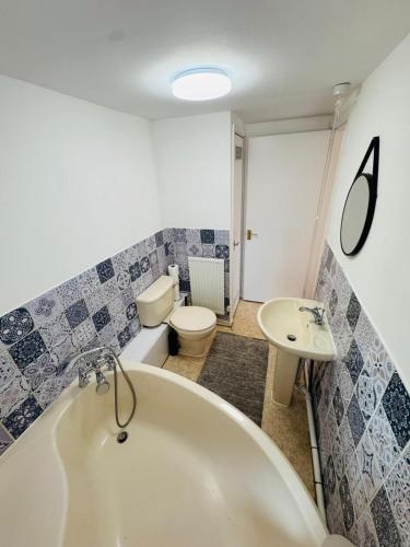 a bathroom with a tub and a toilet and a sink at sinton House in Bransford